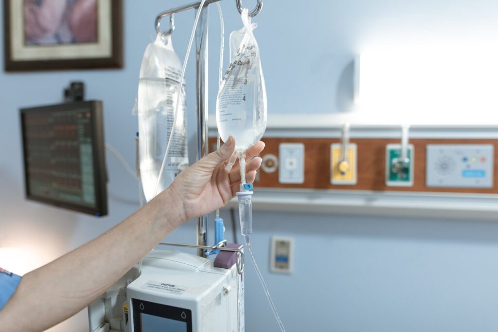 The Art of Drawing Readers In: Your attractive post title goes here Close-up image of an IV drip and hand in a hospital room, illustrating medical care.